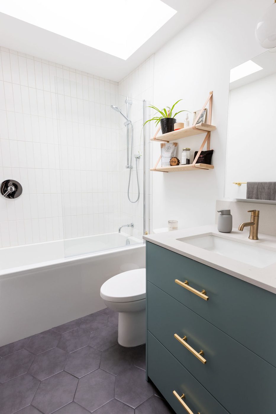 A bathroom with a skylight above the bath, tiled walls and a fitted vanity