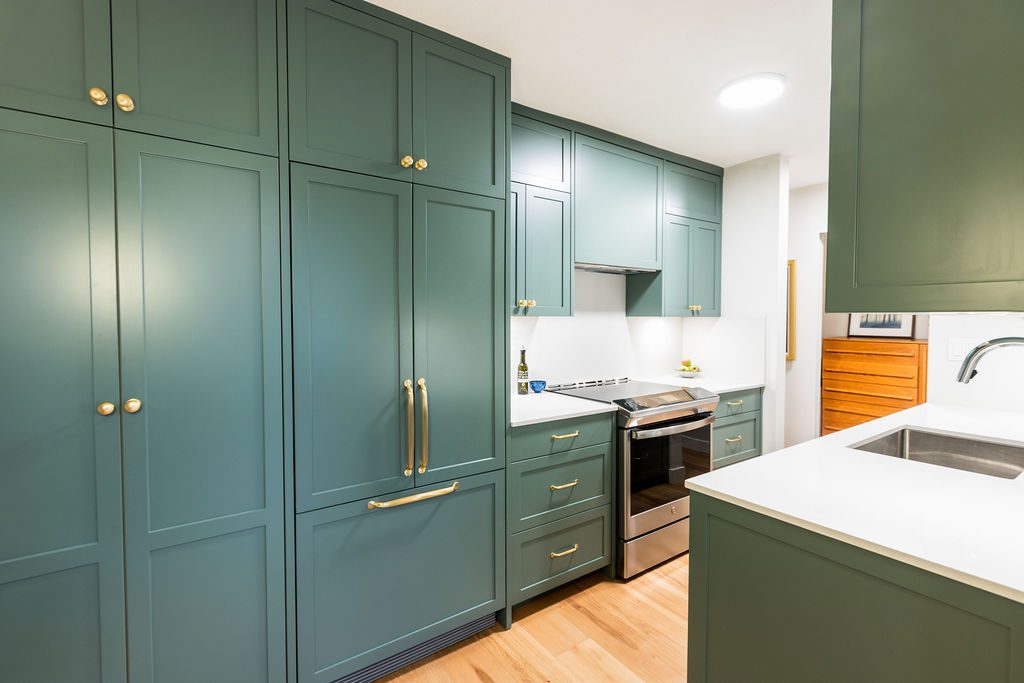 A kitchen in painted shaker joinery with an integrated fridge behind matching panels