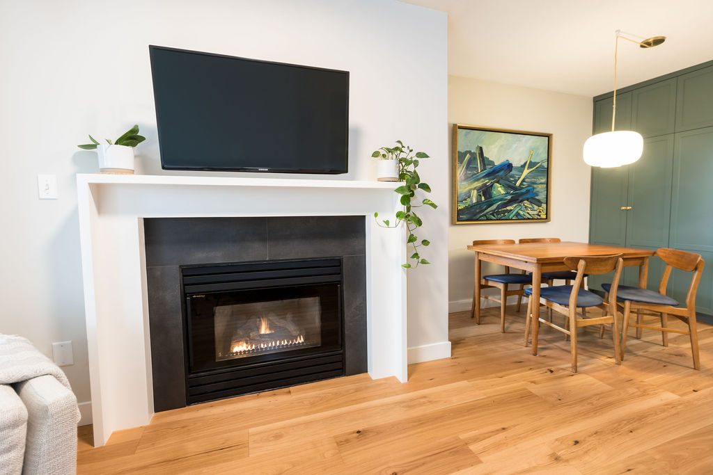 A living and dining room with a fireplace on one side and full height cabinetry on the other