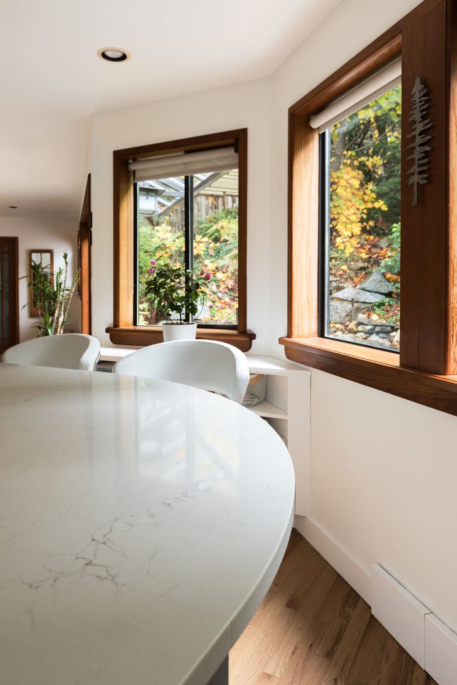 A curved stone breakfast counter set against a wall of timber framed windows