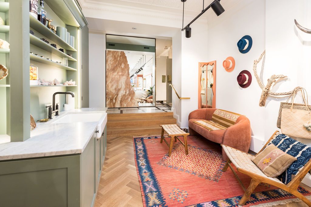 A painted bar with a stone counter and butler sink beside a seating area